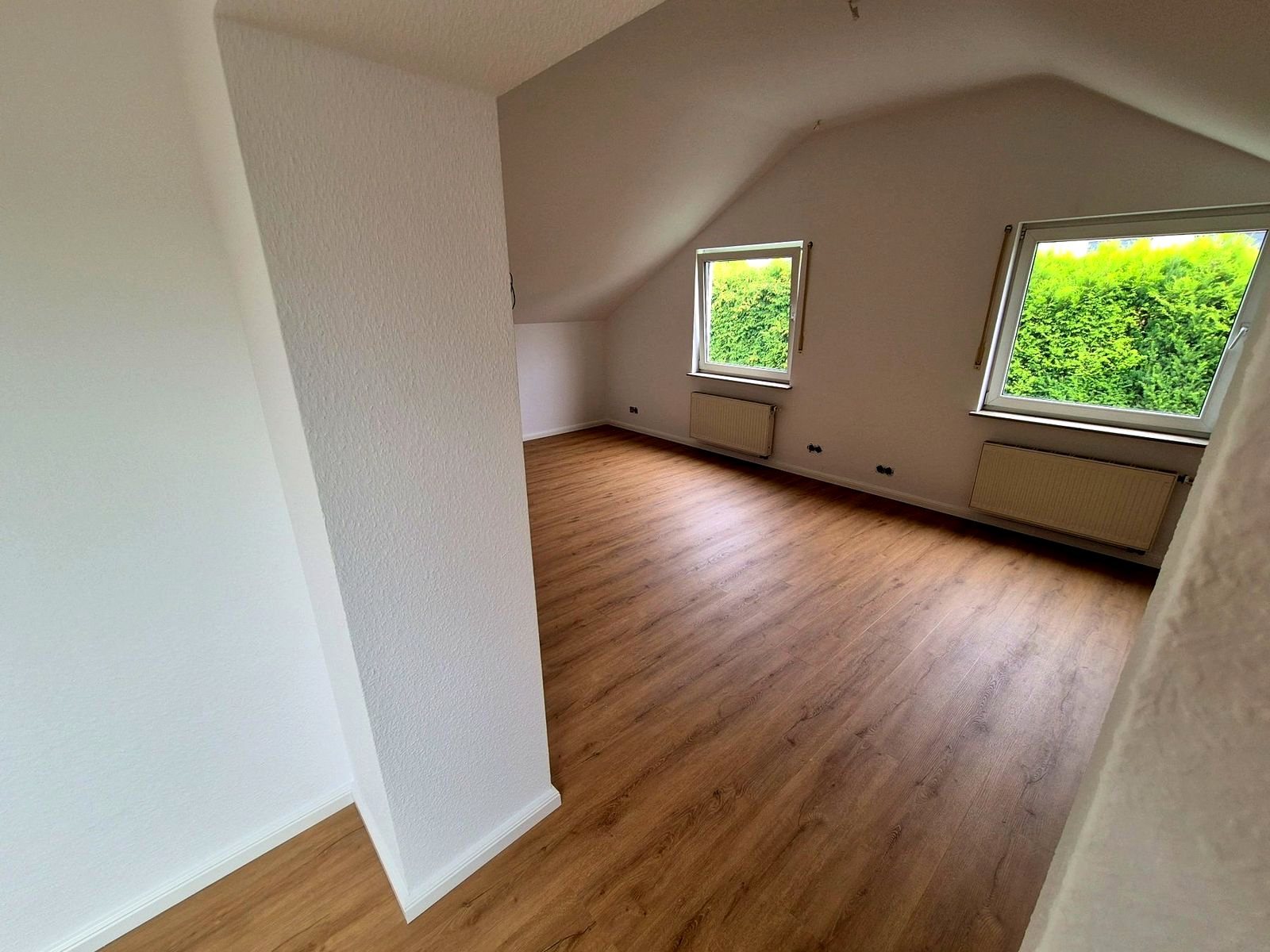 Dachgeschoss mit Dachschräge und Boden in Holzoptik, zwei Fenster