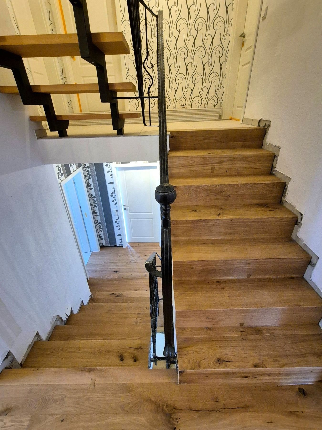 Offene Treppe mit Trittstufen aus Eiche und schwarzem Metallgeländer