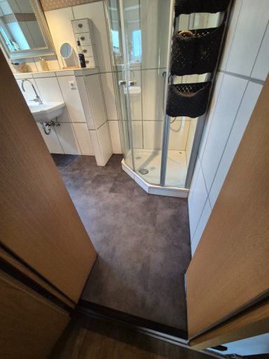 Blick in ein Badezimmer mit Dusche, Waschbecken und Platz für Toilettenartikel.